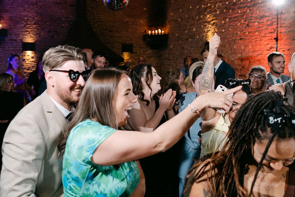Wedding guests dancing inside Stone Barn in the Cotswolds