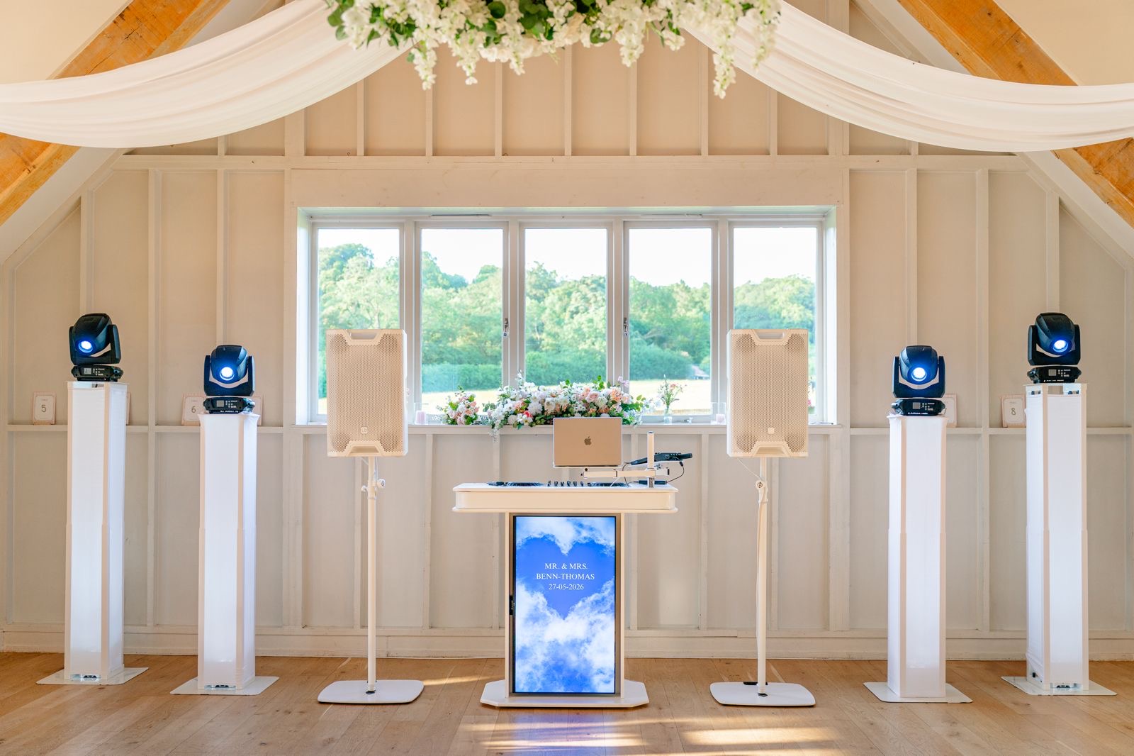 Diamond wedding DJ setup with white speakers and lighting in a barn venue